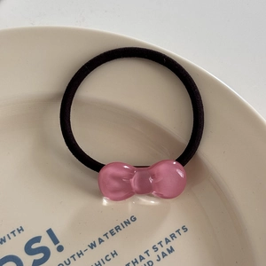 Close-up of a pink jelly resin bow on a high-elastic black hair tie over a cream plate