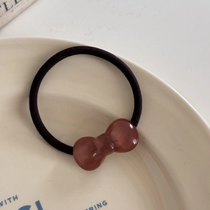 Detail view of a translucent brown resin bow on a high-elastic black hair tie