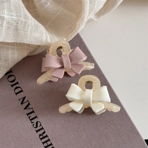 Détail de pinces à cheveux noeud rose et crème sur une surface texturée élégante