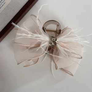 Detail of elegant champagne mesh bow hair claw with white feathers and gray rhinestones