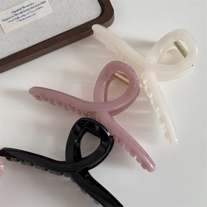 Detail view of large matte resin claw clips in cream white, pink and black with gold springs