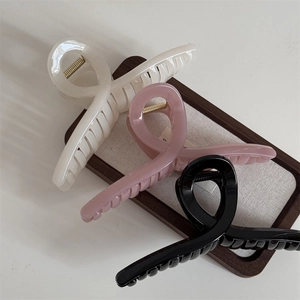 Macro detail of large glossy hair claw clips in beige pink and black finishes