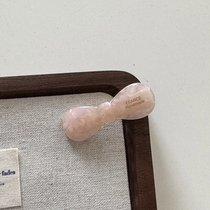 Vue détaillée de la pince à cheveux noeud en acétate rose marbré avec lettrage fait main