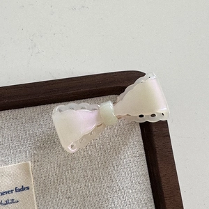 Vue détaillée d'une pince à cheveux nœud en acétate nacré avec bords ondulés et ressort