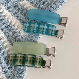 Set of 4 blue and teal plaid and matte hair clips on a soft blue knit background