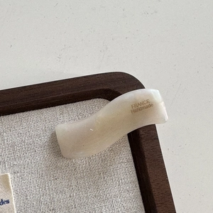 Détail d'une barrette à cheveux ondulée en acétate crème avec lettrage France Handmade