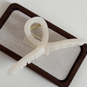 Detail view of the durable golden metal spring on a cream-colored hair claw clip