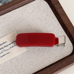 Detailed close-up of a vibrant red rectangular hair clip on a premium jewelry tray