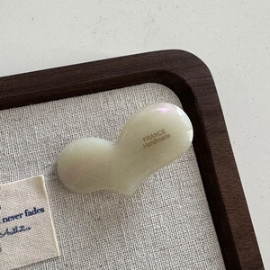 Vue macro d'une pince à cheveux coeur en acétate nacré avec inscription France Handmade