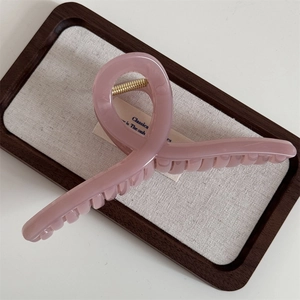 Close-up of a large dusty pink claw clip with cross-wrap design and gold metal spring
