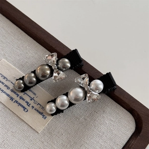 Detailed view of pearl bow hair clips with rhinestones on a black alligator base