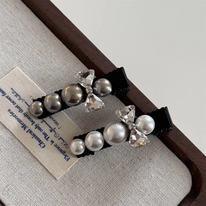 Elegant rhinestone bow and pearl hair clips set on textured fabric with black ribbon base