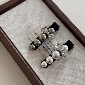 Elegant rhinestone bow and pearl hair clips set on vintage linen background for women