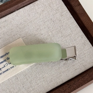 Detailed macro view of the matte light green rectangular acetate hair clip on a silver base