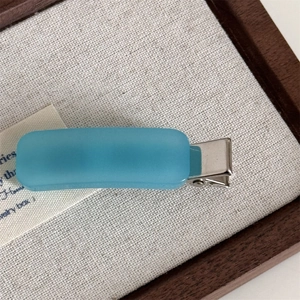 Macro shot of matte sky blue rectangle hair clip with silver metal duckbill base
