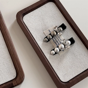 Detailed close-up of retro pearl and crystal hair clips on a linen texture tray