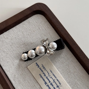 Close-up of elegant bow hair clip with pearls and sparkling heart-shaped rhinestones