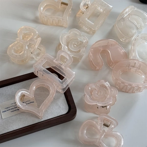 Detail of assorted translucent resin camellia and heart hair claws in cream and pink