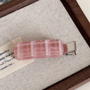 Macro view of pink and white checkered acetate hair clip with silver metal prong