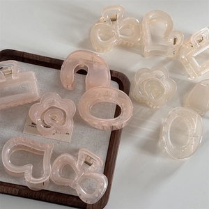 Detailed close-up of translucent camellia and heart hair claws in cream and pink