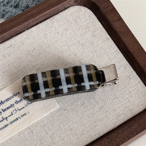Detailed macro view of a brown plaid acetate hair clip on a metal alligator base