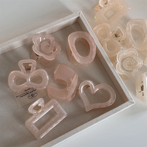 Close-up of translucent peach camellia and heart-shaped claw clips in a display tray