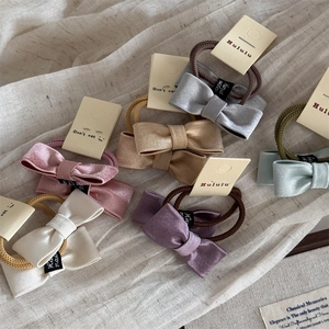Set mit Satin-Bogen-Haarspangen in Pastellfarben mit handgemachtem Etikett auf Baumwolle