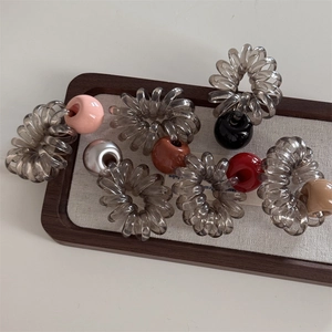 Élastiques à cheveux spirale avec perles colorées présentés sur un plateau en bois