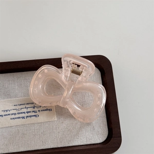 Close-up of a translucent pink camellia flower hair claw clip with gold metal spring