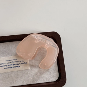 Pink translucent acrylic hair claw clip on wooden tray with white fabric background