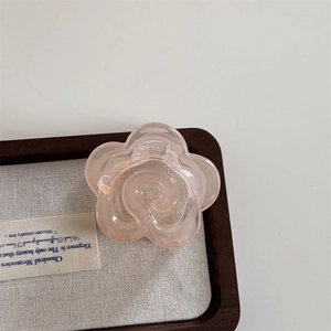 Close-up of translucent pink camellia flower hair claw clip on a luxury display tray