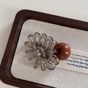 Détail d'un élastique spirale gris avec une perle décorative marron sur bois élégant