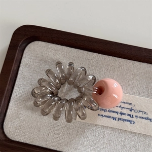 Macro d'élastique spirale gris avec perle rose sur un plateau en bois rustique