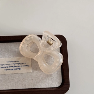 Detailed view of the translucent camellia resin bow hair claw with gold spring mechanism