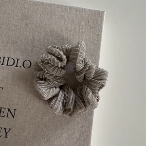 Close-up of champagne gold pleated scrunchie with metallic silk texture and fine pleats