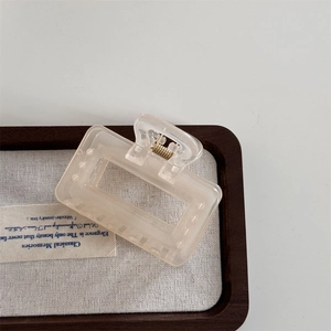 Close-up of translucent beige matte square hair claw clip with golden metal spring