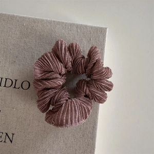 Close-up detail of pleated texture on a mauve silk-feel elastic hair scrunchie