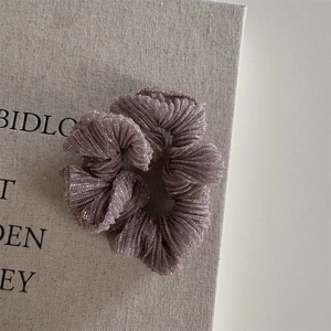 Close-up of pleated metallic hair scrunchie with shimmering texture on a book cover