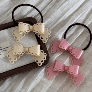 Détails de barrettes à nœuds en acétate et chouchous en tons crème et rose pastel