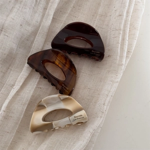 Dettaglio di tre mollette in acetato marrone, tartaruga e beige con stampa Barrette