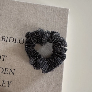 Detail of a black sparkling scrunchie with silver glitter texture shaped into a heart