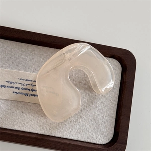 Detailed view of a translucent cream hair claw clip with a sleek organic curved design