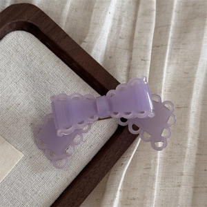 Gros plan d'une pince à cheveux nœud en acétate violet clair avec bords ondulés