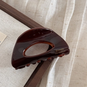 Dettaglio della molletta per capelli in acetato marrone con scritte dorate Barrette La France