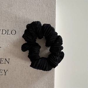 Detail of black pleated scrunchie showing shiny thread texture and soft elastic fabric