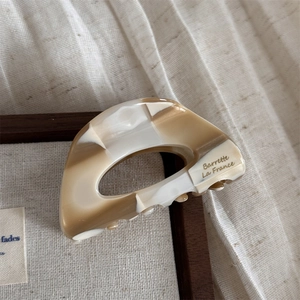 Dettaglio della molletta per capelli in acetato marmorizzato con scritta dorata elegante