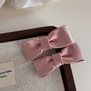 Nahaufnahme von rosa Schleifen-Haarspangen aus geripptem Ripsband auf einem Holztablett