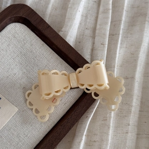 Gros plan sur la barrette à cheveux nœud crème avec d'élégants bords festonnés