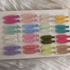 Macro display of 16-color macaron seamless matte hair clips on beige textured fabric