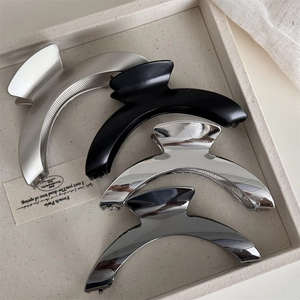 Detailed set of four curved metal hair claws in matte and glossy silver and black finishes